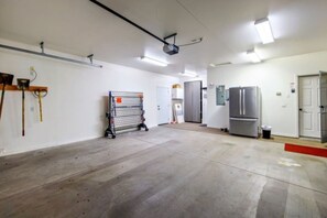 A spacious indoor area with a large open floor, a projector mounted on the ceiling, and a refrigerator against the wall. - Sleeps 12 w/ ping pong & pool table| comfort + (Lake Havasu City)