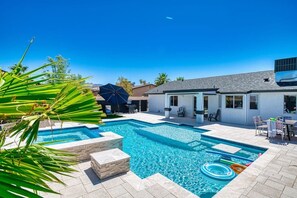 A swimming pool with a stone border, a patio area with outdoor furniture, and a covered seating area. - Pool + Spa Retreat | Game Garage | Trailer Parking (Lake Havasu City)