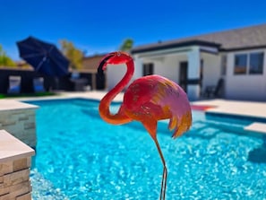 A flamingo standing by a swimming pool with a clear blue sky in the background. - Pool + Spa Retreat | Game Garage | Trailer Parking (Lake Havasu City)