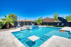 Une piscine rectangulaire bordée de pierres, entourée d’une terrasse dallée.