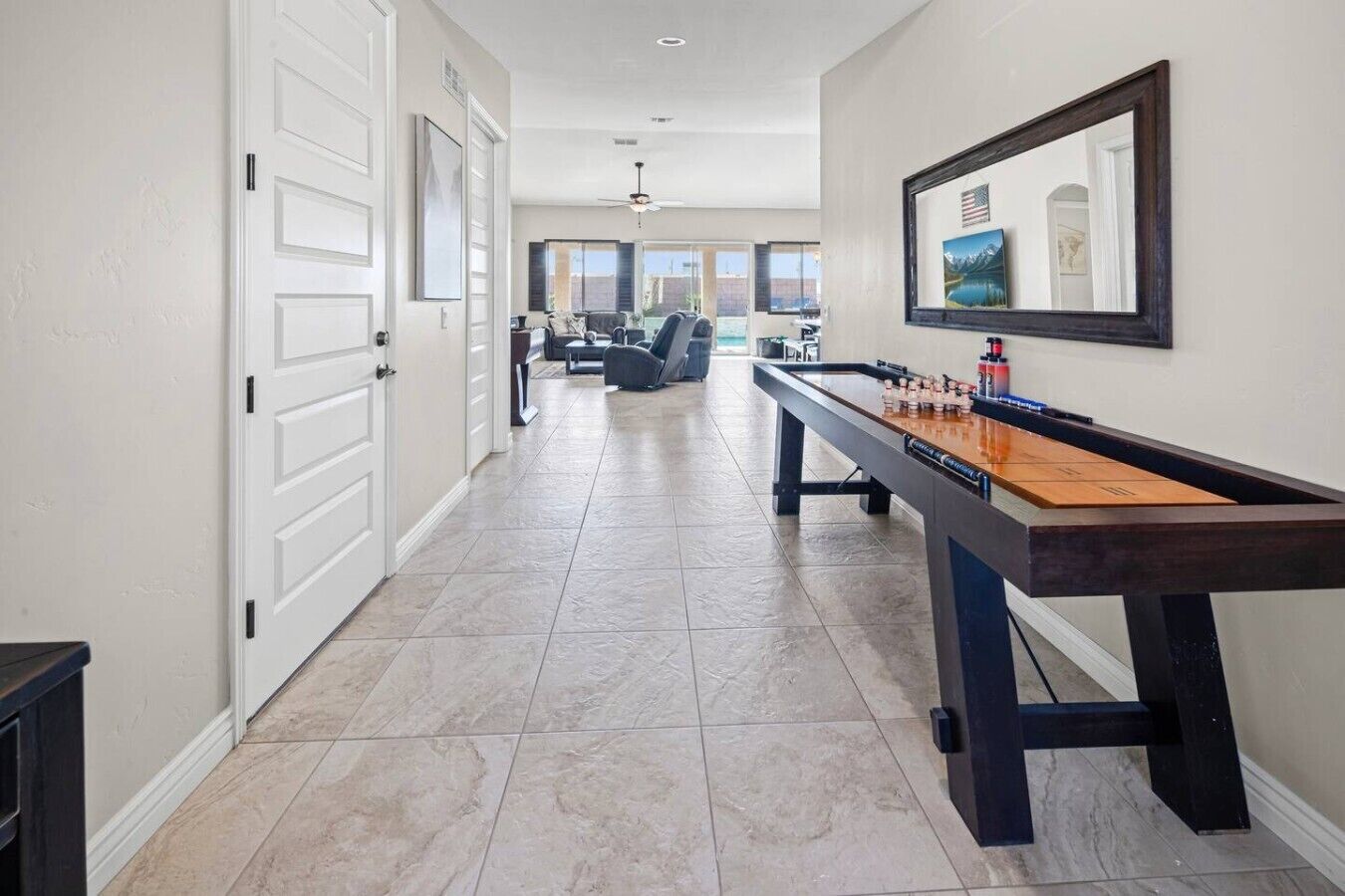 A hallway with a pool table, a door, and a framed picture on the wall.