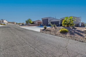 A residential street with houses, a clear sky, and a dry, rocky landscape. - Pool, Spa & 100” TV | Near Windsor (Lake Havasu City)