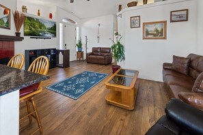 Un salon avec un canapé en cuir marron, une table basse, un tapis et un coin repas comprenant des chaises et une table.