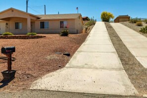 A residential street with a single-story house, a mailbox, and a sidewalk. - Pet-Friendly | Sunset View Deck | Pool & Spa (Lake Havasu City)