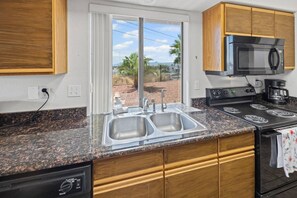A kitchen with a double sink, a microwave, a stove, and wooden cabinets. - Pet-Friendly | Sunset View Deck | Pool & Spa (Lake Havasu City)