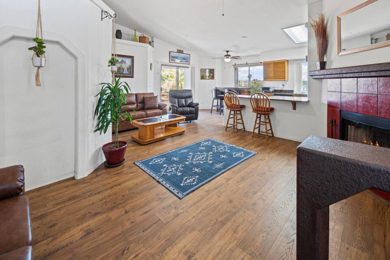 A spacious living room with a fireplace, wooden flooring, and a dining area with chairs and a table.