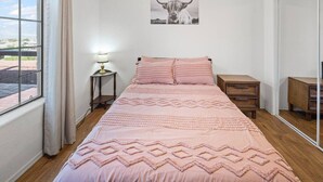 A bedroom with a bed, bedside tables, a lamp, a mirror, and a picture on the wall.