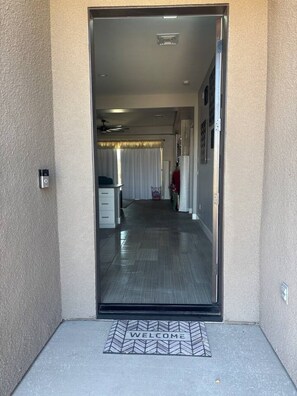 A doorway leading to a hallway with a welcome mat, a ceiling fan, and a door with a handle. - Resort-Style Entertainer | Near Launches (Lake Havasu City)