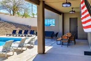 A poolside area with lounge chairs, a table, and a flag. - Resort-Style Entertainer | Near Launches (Lake Havasu City)