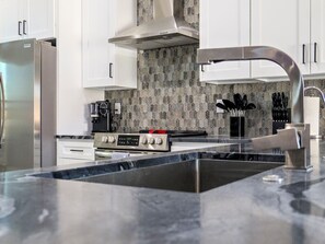 A modern kitchen with a stainless steel refrigerator, a gas stove, and a large sink. - Resort-Style Entertainer | Near Launches (Lake Havasu City)
