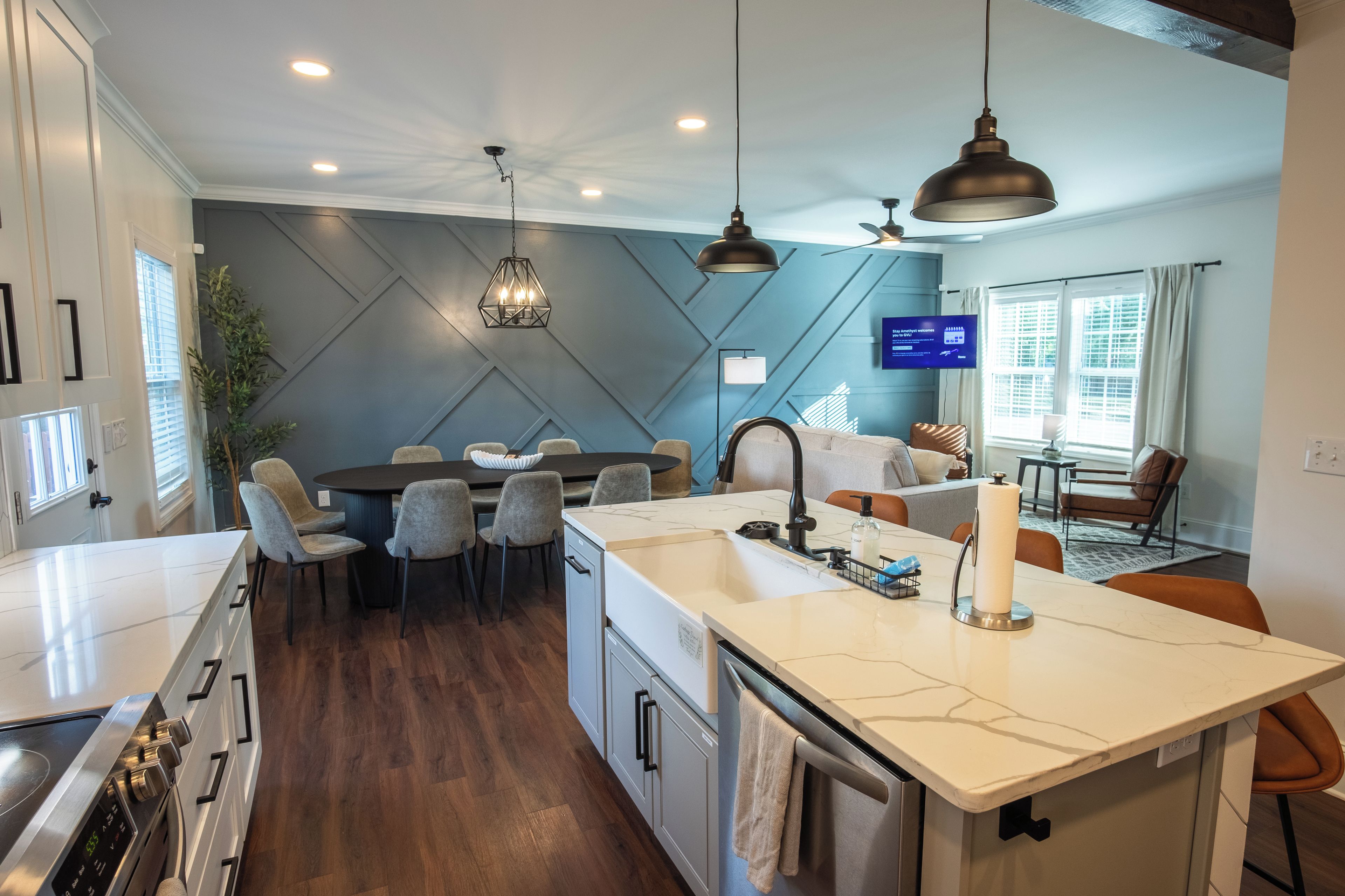 Una cocina moderna con una isla central, comedor y sala de estar con televisor.
