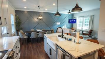 Una cocina moderna con una isla central, comedor y sala de estar con televisor.