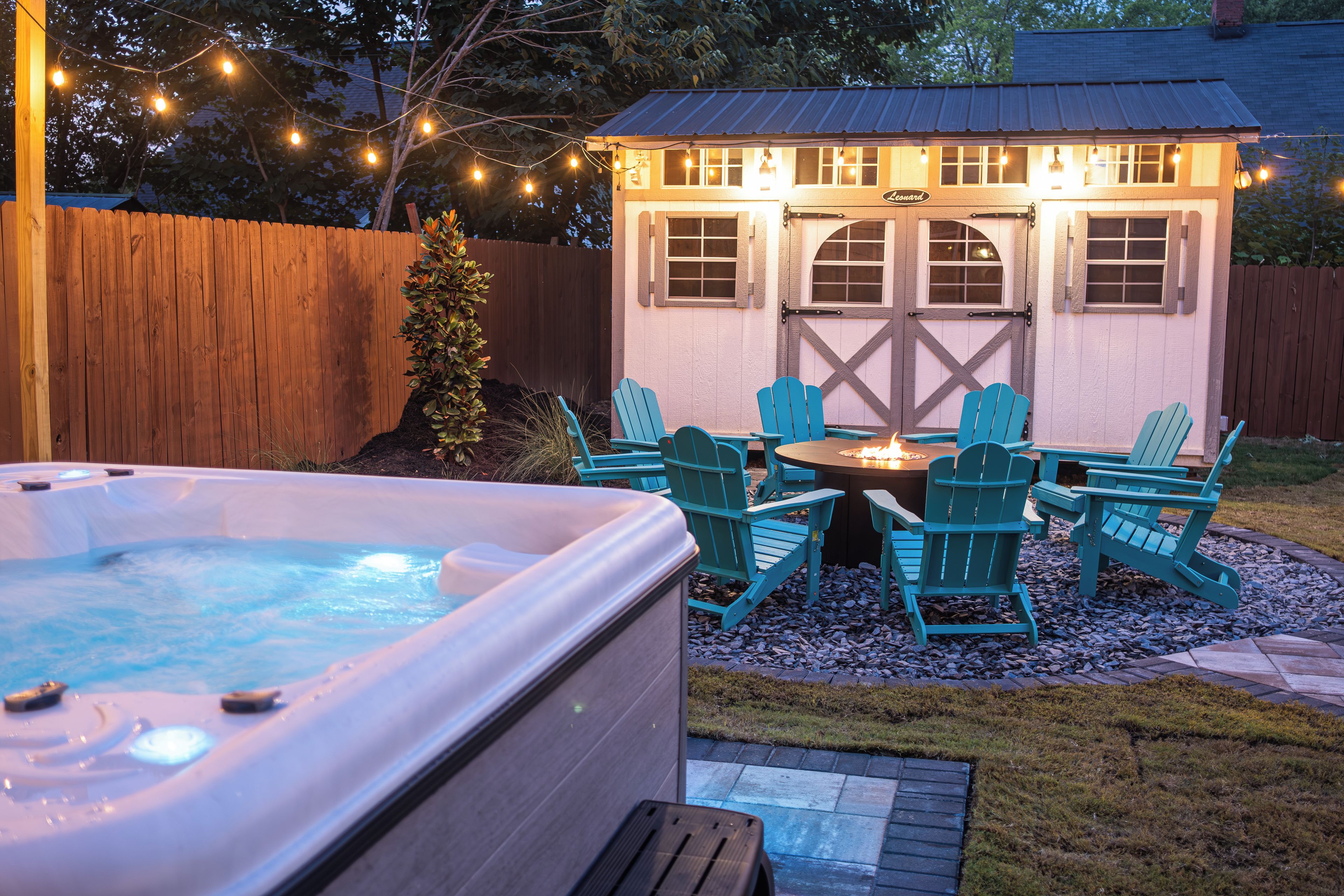 Ein Whirlpool mit Liegestühlen und einer kleinen Feuerstelle im Garten.