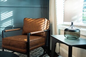 Ein brauner Ledersessel mit Metallgestell, platziert neben einem Tisch mit einer Lampe.