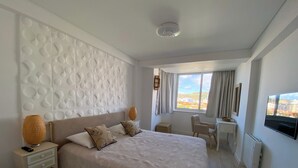 Una habitación de hotel moderna con una cama grande, un escritorio y vistas a la ciudad.