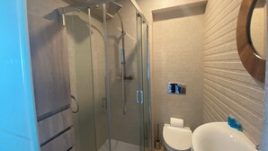 Un baño moderno con ducha de vidrio, inodoro y lavamanos.
