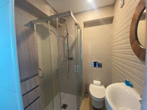 A modern bathroom with a glass-enclosed shower, a toilet, and a sink. - Sea View Apartment - Right on the Beach in Costa da Caparica (Costa de Caparica)