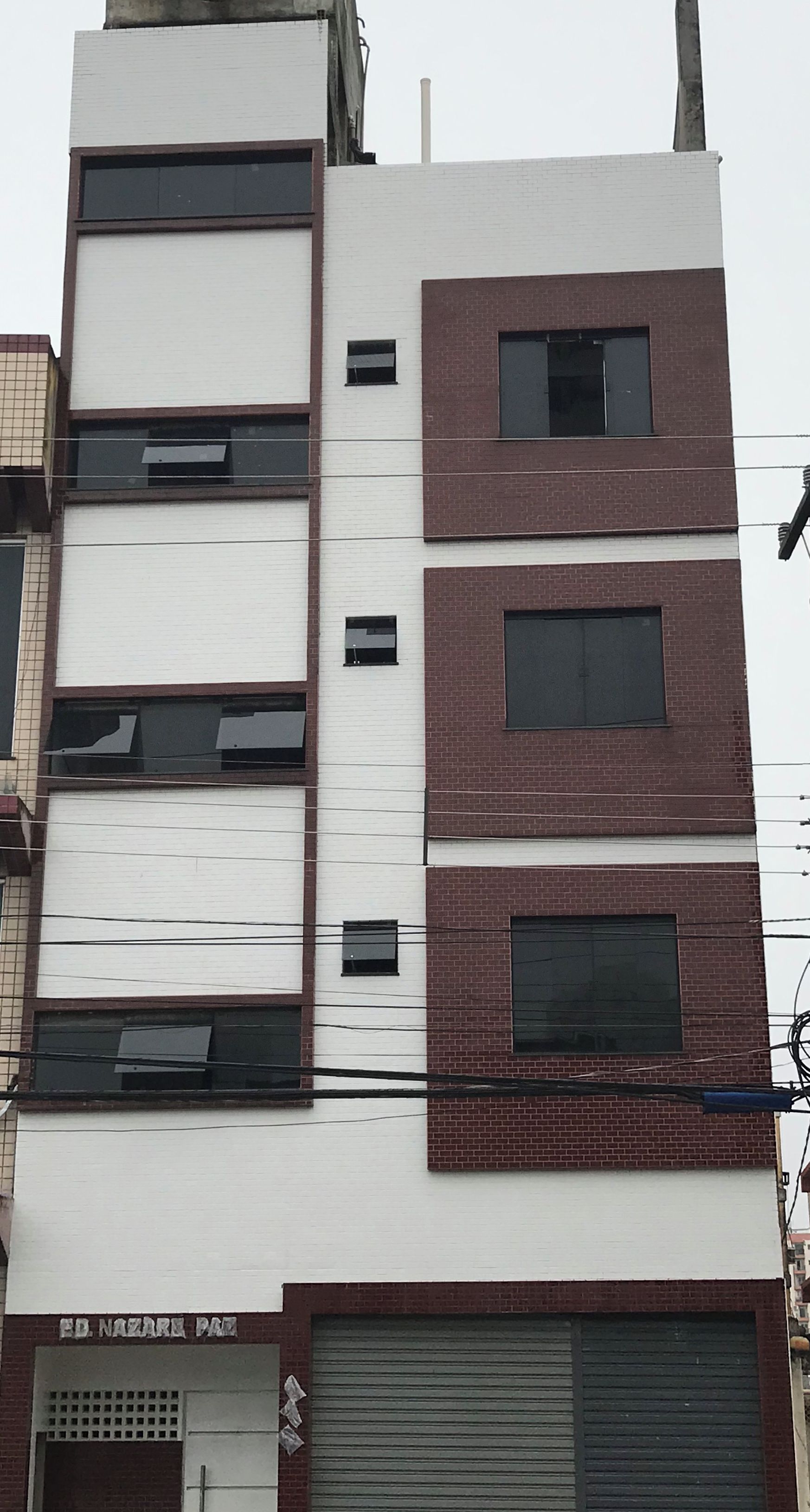 A multi-story building with a white facade and red brick accents.