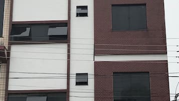 Ein mehrstöckiges Gebäude mit weißer Fassade und roten Backsteinakzenten.