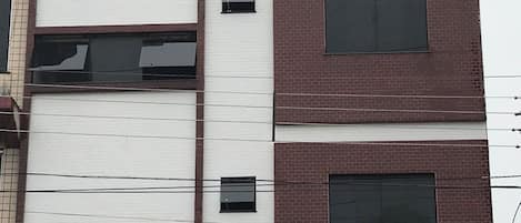A multi-story building with a white facade and red brick accents.