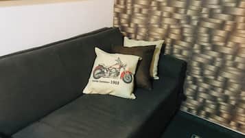 Un canapé de couleur sombre agrémenté d’un coussin orné d’un motif représentant une moto et de l’année 1903.