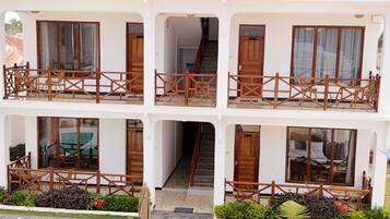 Un hotel de varios pisos con balcones, piscina y mobiliario exterior.