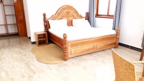 Una cama de madera con cabecera, una mesita de noche y una silla.