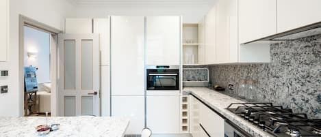 A modern kitchen with white cabinets, a granite countertop, and a built-in oven.