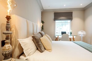 Un dormitorio con cama, mesita de noche, lámpara y ventana con vistas.