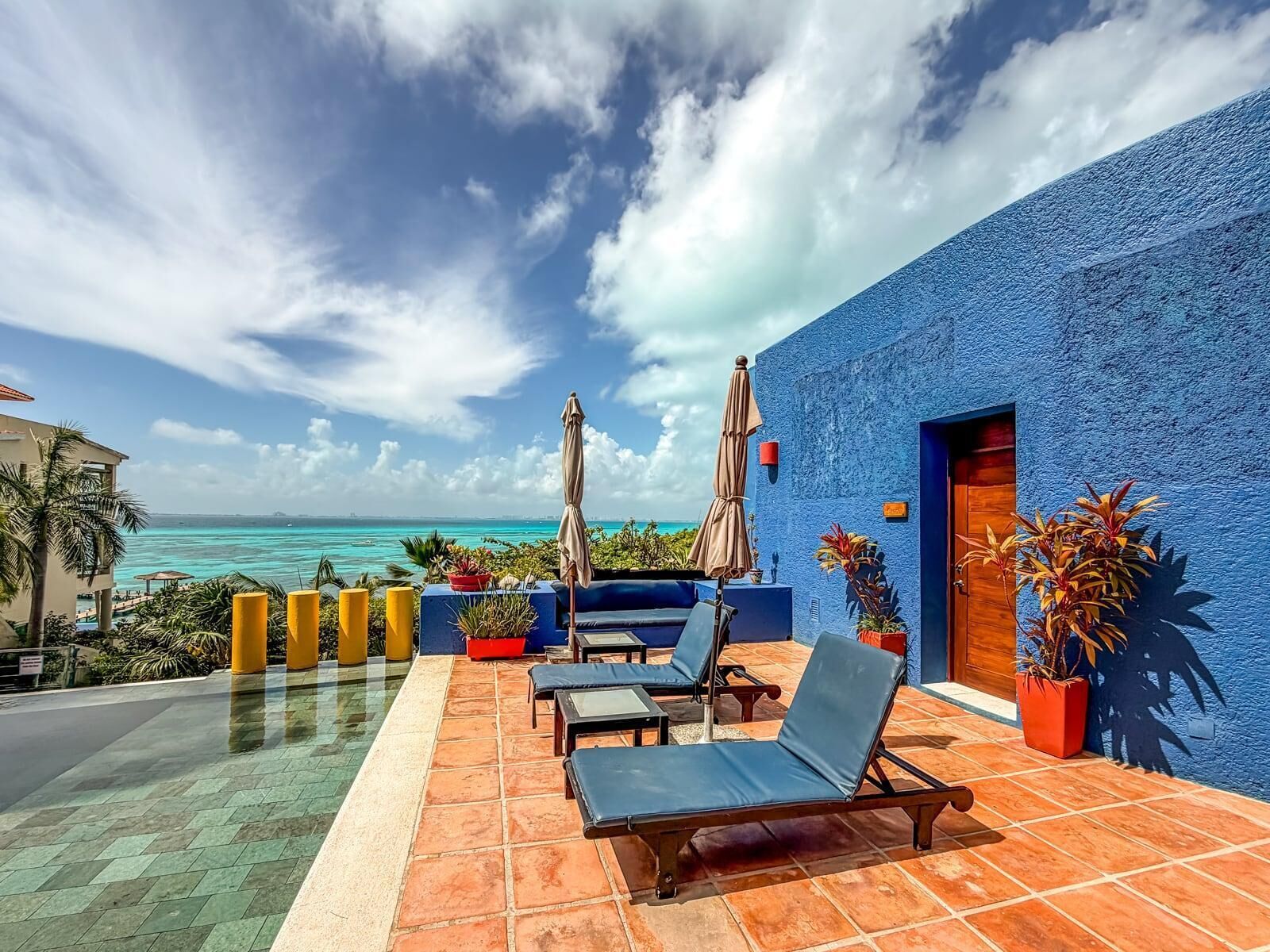 A terrace with lounge chairs, a pool, and a view of the ocean.