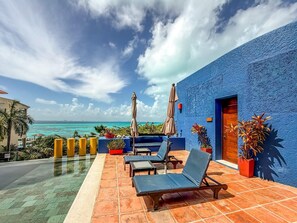 A terrace with lounge chairs, a pool, and a view of the ocean. - Junior Suite Garden View at Casa de los Suenos (Isla Mujeres)