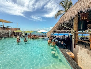 Ein Poolbereich mit klarem Wasser, einer Bar und Sonnenschirmen.