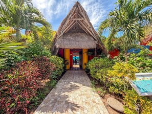 A thatched-roof structure with a paved pathway leading to it, surrounded by lush tropical vegetation. - Junior Suite Garden View at Casa de los Suenos (Isla Mujeres)