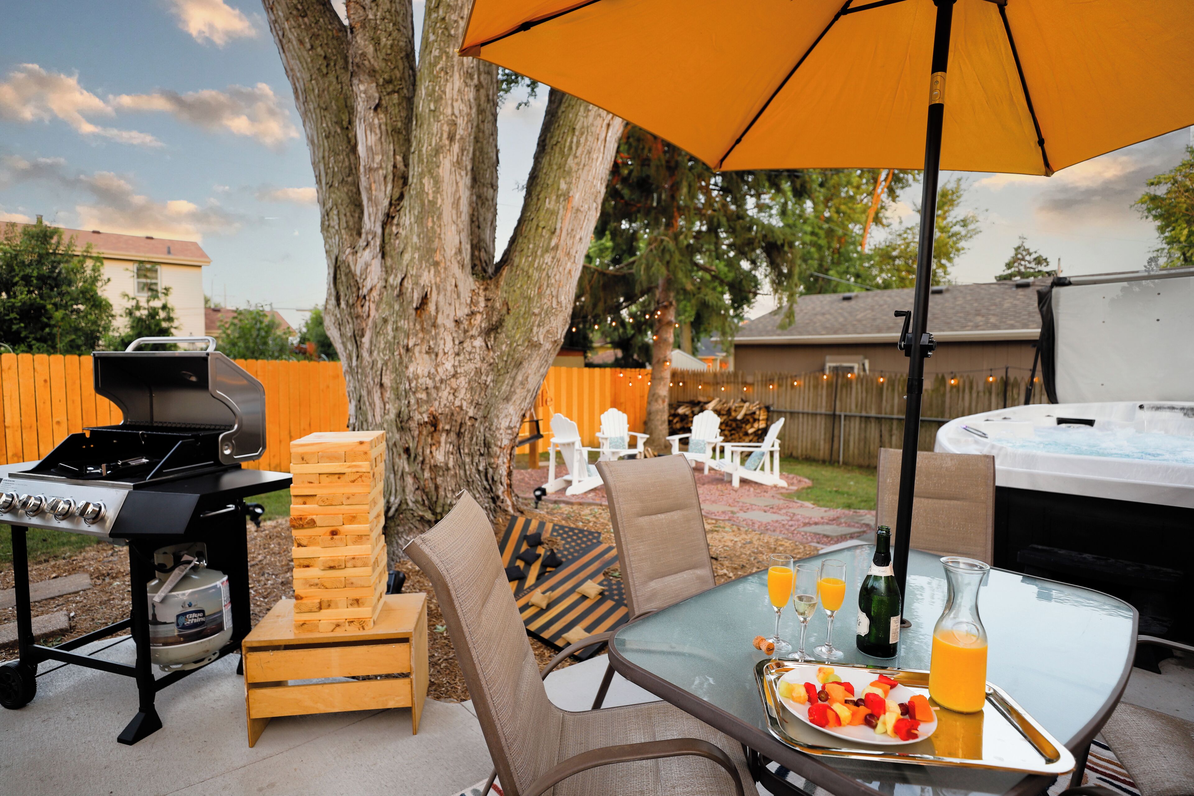 An outdoor patio with a grill, wooden blocks, seating, and a hot tub.