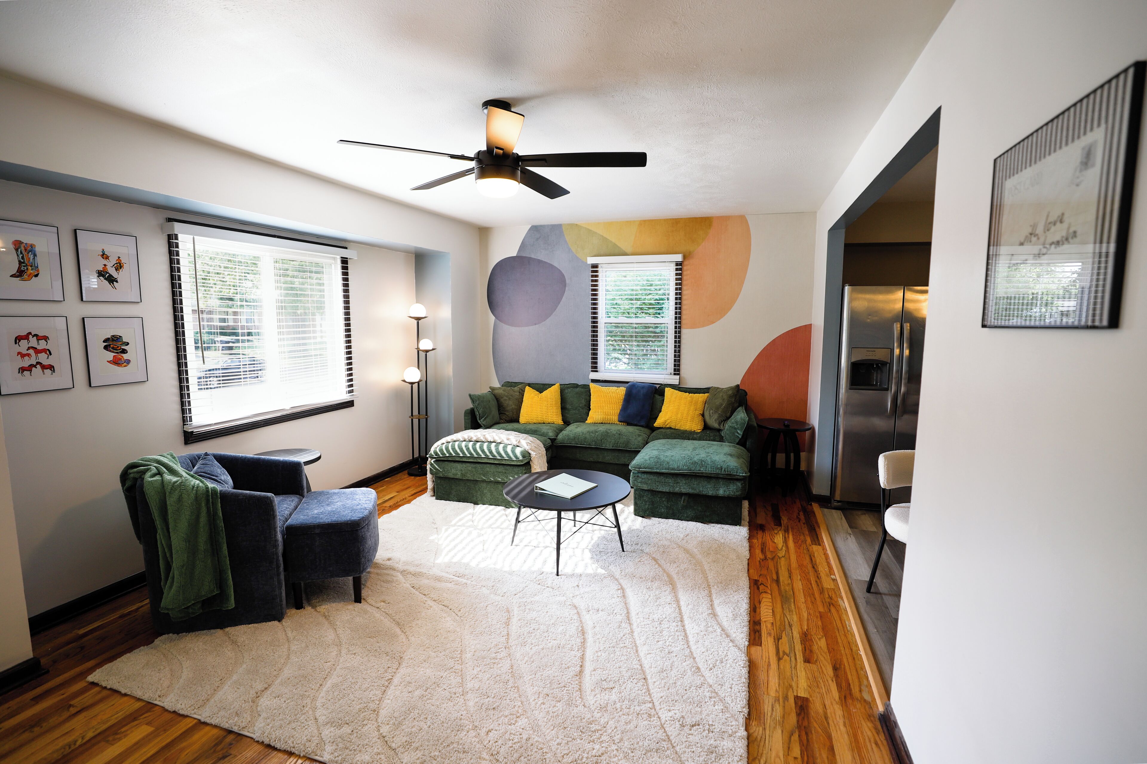 A modern living room with a green sofa, a coffee table, and a ceiling fan.