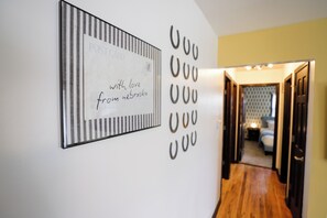 A hallway with a framed card on the wall and a series of hanging circular decorations. - Hot Tub_Theater_Game Room_Poker Table (Omaha)