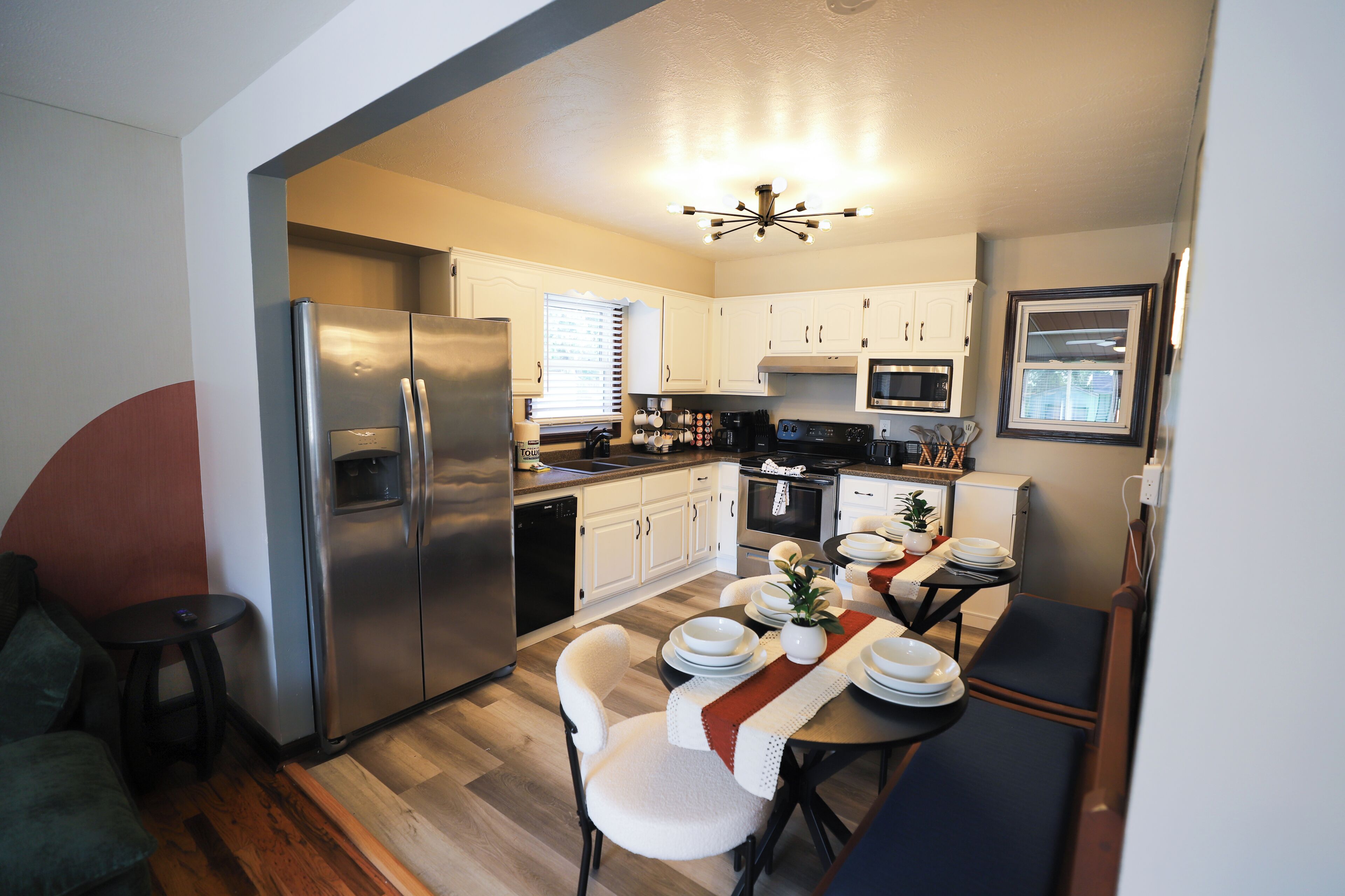 A compact kitchen with modern appliances, a dining area with a table set for four, and a cozy seating area.