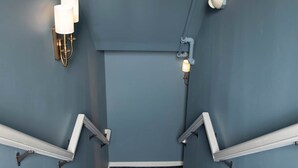 A staircase with a patterned carpet, wall-mounted light fixtures, and a handrail. - The Bloomberg at Bloomberg Suites (Chanhassen)