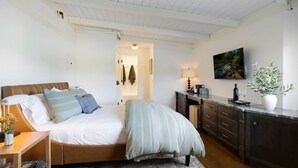 A bedroom with a bed, bedside table, lamp, and a painting on the wall. - The Bloomberg at Bloomberg Suites (Chanhassen)