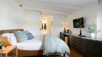 Un dormitorio con cama, mesita de noche, lámpara y un cuadro en la pared.