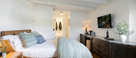 A bedroom with a bed, bedside table, lamp, and a painting on the wall.