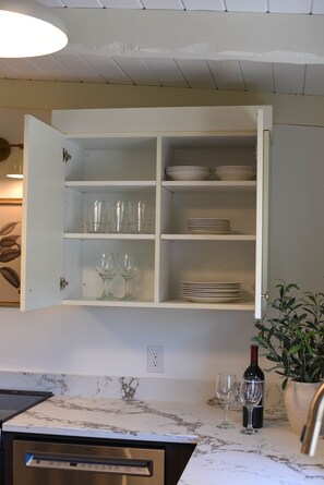 A kitchen with a built-in cabinet containing glassware and plates.