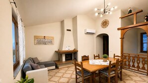 A living room with a sofa, a dining table with chairs, a fireplace, and a clock on the wall. - Sunset in Seu, 150 meters from the beach. Ideal for families and couples. (Funtana Meiga)