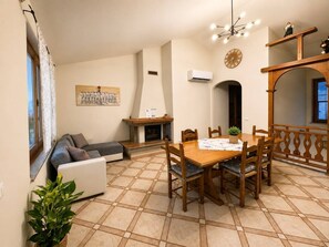 Ein Wohnzimmer mit einer Couch, einem Esstisch mit Stühlen, einem Kamin und einer Wanduhr.