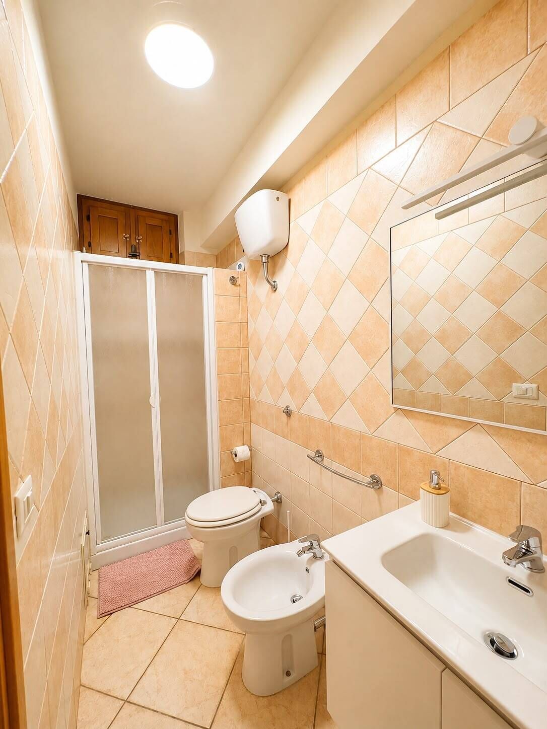 A bathroom with a shower, toilet, bidet, and sink.