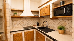 A compact kitchen with wooden cabinets, a black countertop, a microwave, and a built-in oven. - Sunset in Seu, 150 meters from the beach. Ideal for families and couples. (Funtana Meiga)