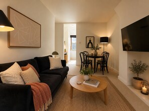Ein modernes Wohnzimmer mit einer schwarzen Couch, einem Couchtisch und einem Essbereich mit Stühlen und einem Tisch.