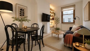 Ein modernes Wohnzimmer mit Essbereich, einer Couch, einem Fernseher und einem Fenster.