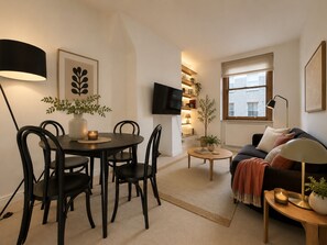 A modern living room with a dining area, a sofa, a TV, and a window. - Stylish 2-BRs Flat with AC near Oxford Street (London)