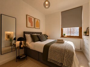 Ein Schlafzimmer mit einem Bett, einem Nachttisch, einer Lampe und Kunstwerken.